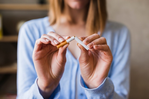 Foto mujer mano rompiendo cigarrillo