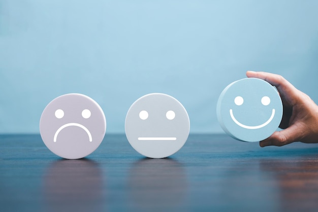 Mujer con la mano, rostro feliz, sonrisa, icono facial en un objeto azul redondo, experiencia del cliente y servicio con satisfacción, concepto de pensamiento positivo, evaluación de la salud mental, Día Mundial de la Salud Mental.