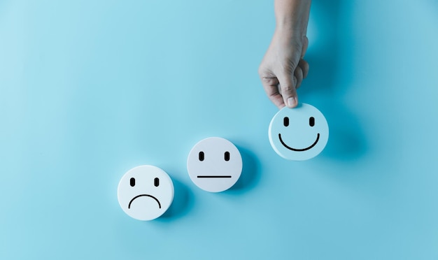 Mujer con la mano, rostro feliz, sonrisa, icono facial en un objeto azul redondo, experiencia del cliente y servicio con satisfacción, concepto de pensamiento positivo, evaluación de la salud mental, Día Mundial de la Salud Mental.