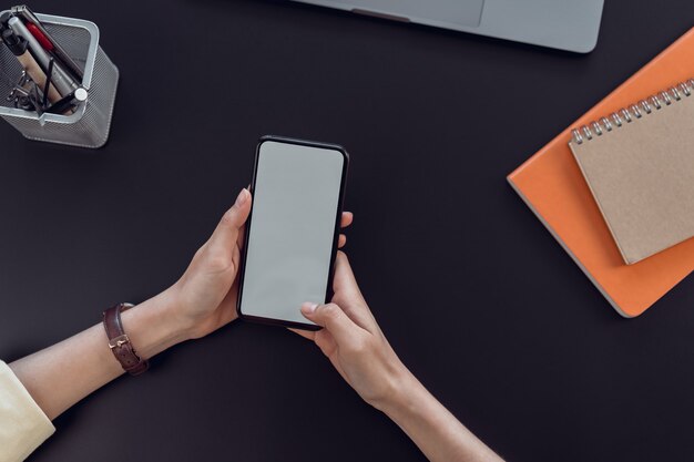 Mujer mano sostenga el teléfono inteligente con pantalla en blanco copia espacio.