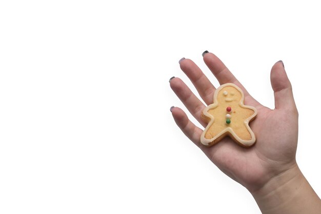 Mujer mano sosteniendo galleta de hombre de pan de jengibre sobre fondo blanco.