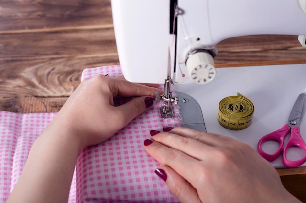 mujer de mano con vestido en la máquina de coser