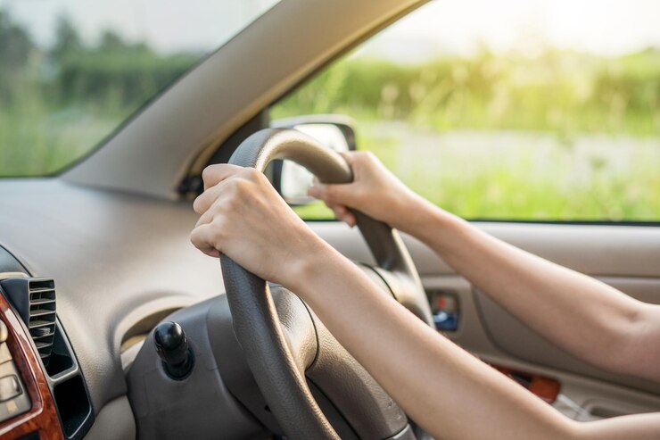 Mujer de la mano en el volante de un automóvil mientras conduce el parabrisas y la carretera