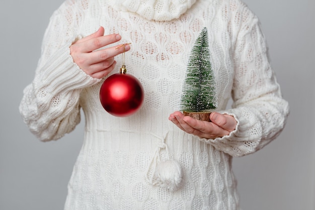 Foto mujer mantenga el árbol de navidad y un adorno de fondo de vacaciones de navidad o año nuevo