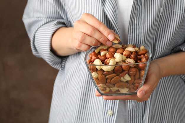 Foto mujer mantenga cuenco con diferentes frutos secos. alimentación saludable