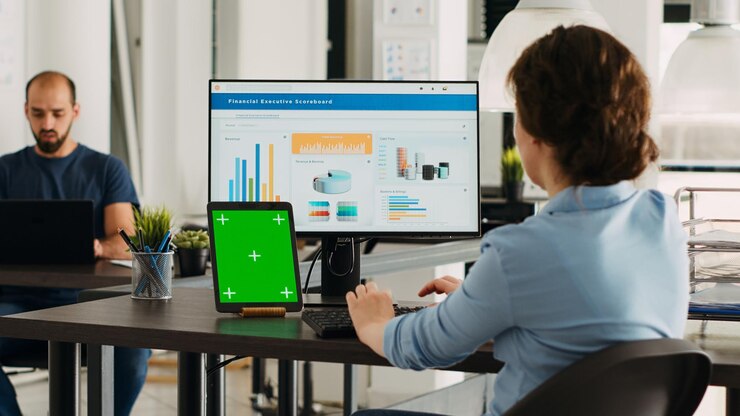 Foto mujer mantiene una tableta con pantalla verde en el escritorio trabajando en el plan de desarrollo para el presupuesto de la agencia de inicio adulto empleado mirando una plantilla de maqueta de copyspace aislada en la oficina de la compañía