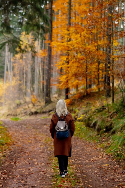 Mujer en manto y mochila es paseos por el bosque en otoño