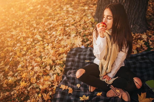 Mujer con manzana roja en el parque otoño.