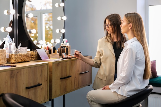 Mujer y maquilladora mirando al espejo