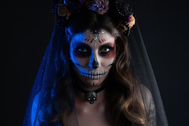 Mujer con maquillaje artístico espeluznante y flores frescas en la cabeza de pie preparada para halloween