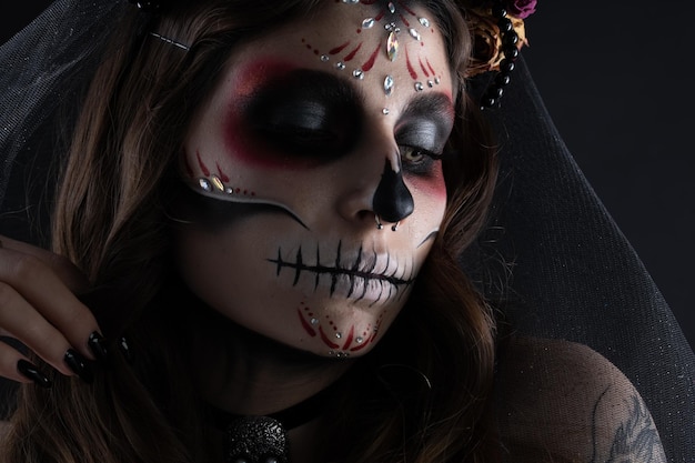 Mujer con maquillaje artístico espeluznante y flores frescas en la cabeza de pie preparada para halloween