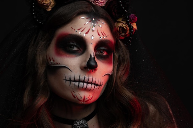 Mujer con maquillaje artístico espeluznante y flores frescas en la cabeza de pie preparada para halloween