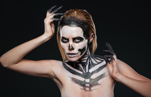 Mujer con maquillaje aterrador gótico posando sobre fondo negro