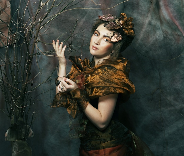 Mujer con maquillaje brillante con ramas secas