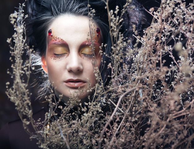 Mujer con maquillaje brillante con ramas secas