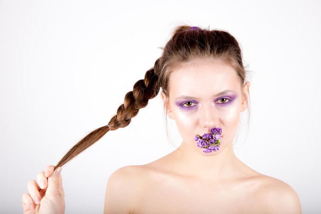 Mujer con maquillaje creativo y flores en la boca.