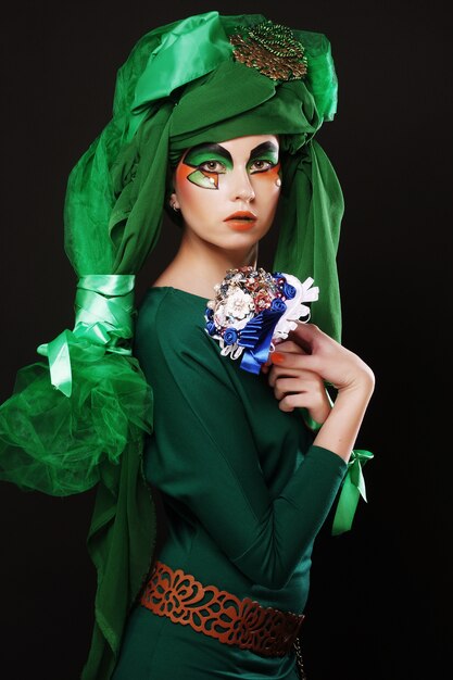 Mujer con maquillaje creativo sosteniendo un ramo de joyas