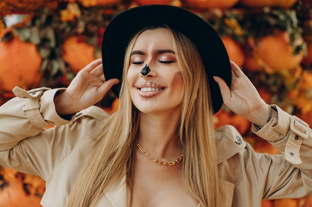 Foto mujer con maquillaje de halloween de pie junto a calabazas de halloween