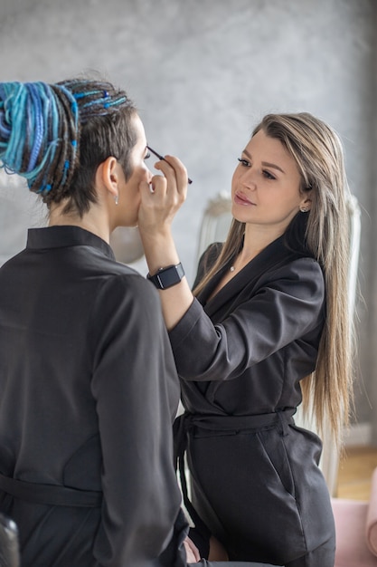 Mujer maquillaje maestro aplicando rubor en polvo de base de tono de piel en la cara use cepillo en el salón de belleza