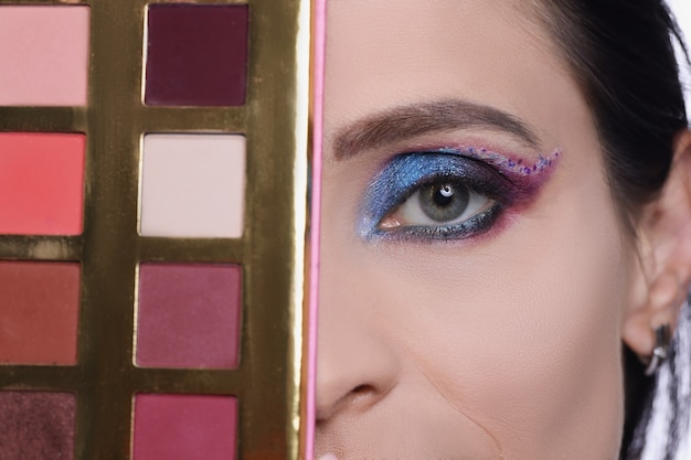 Foto mujer con maquillaje de noche tiene selección de paleta de sombra de ojos del concepto de cosméticos