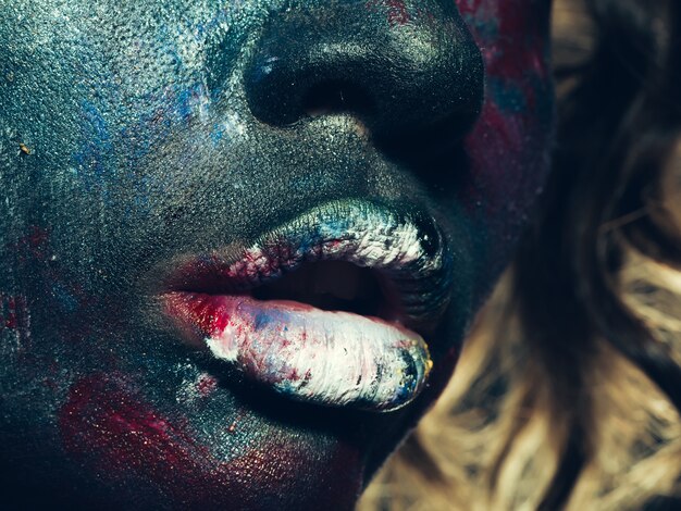 Mujer con maquillaje de pintura inusual en primer plano de la cara y los labios