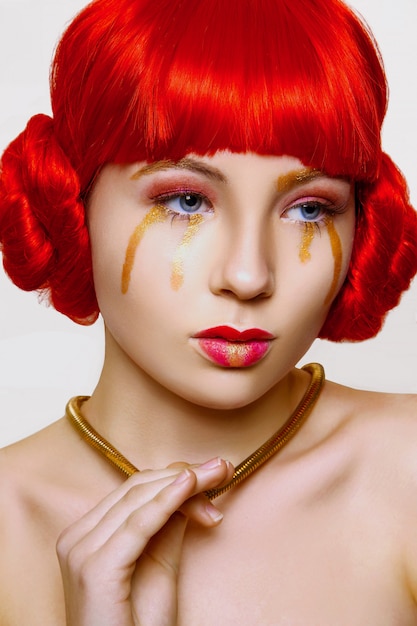 Mujer con maquillaje rojo y dorado y cabello rojo