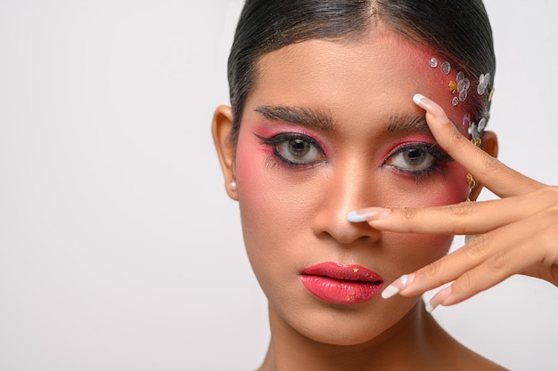 Mujer con maquillaje rosa y adornos en su rostro aislado en blanco