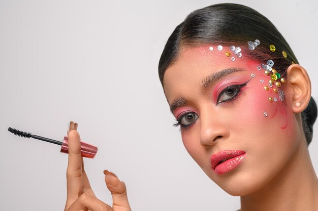 Mujer de maquillaje rosa con pincel de cejas aislado en blanco