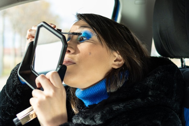 Mujer maquillándose dentro de un auto usando un espejo
