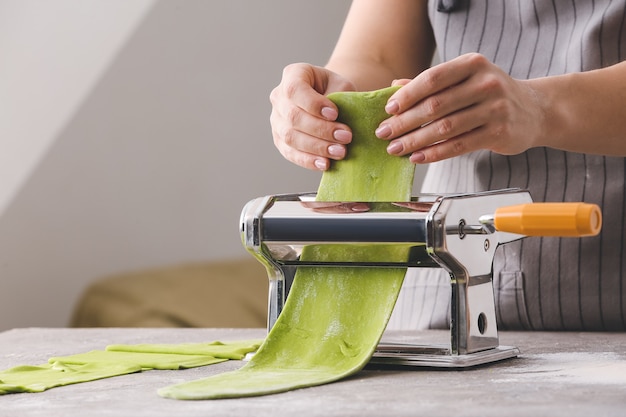 Mujer con máquina de masa y pasta en la mesa