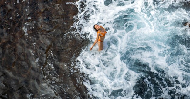 Mujer en el mar cerca de las olas vista superior tiro aéreo