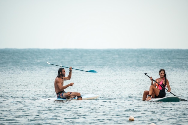 Mujer de mar y hombre en la silueta de una joven feliz y un hombre surfeando en la tabla de surf confiados