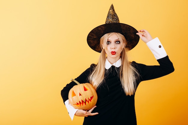 Mujer maravilla emoción de pie contra una calabaza amarilla sosteniendo y toca su sombrero