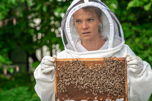 Mujer con un marco de cera con abejas en apicultura