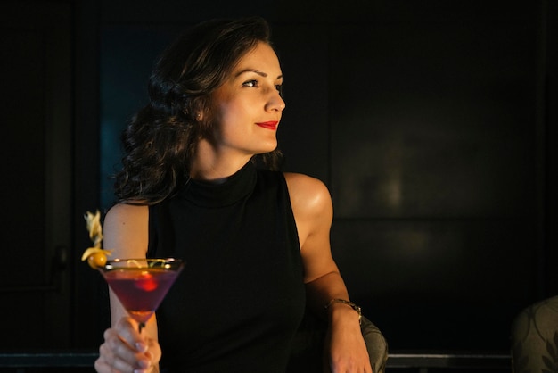 Foto mujer con martini mirando hacia otro lado mientras está sentada en un restaurante