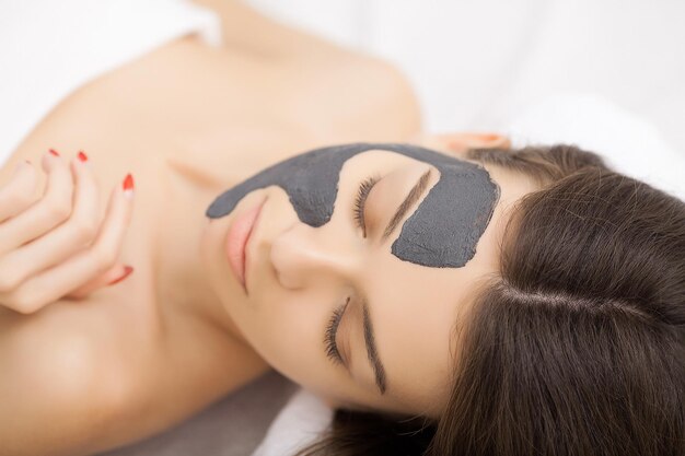 Mujer con máscara en la cara en el salón de belleza spa.