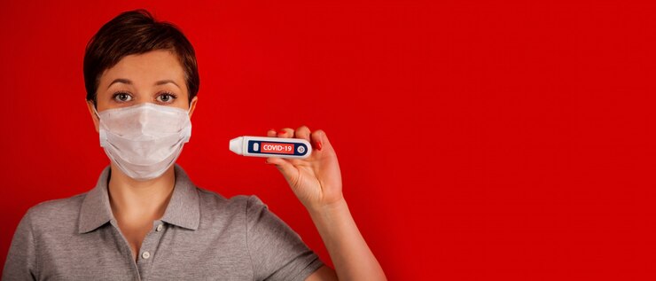 Foto una mujer con una máscara con un coronavirus lee su temperatura en un termómetro con la inscripción covid-19. prueba positiva para coronavirus. el nuevo coronavirus covid-19