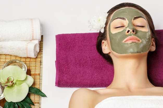 Mujer con máscara facial de arcilla en el spa de belleza Concepto de belleza para el cuidado de la piel Retrato de una hermosa gir