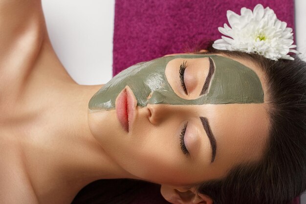 Mujer con máscara facial de arcilla en el spa de belleza Concepto de belleza para el cuidado de la piel Retrato de niña hermosa