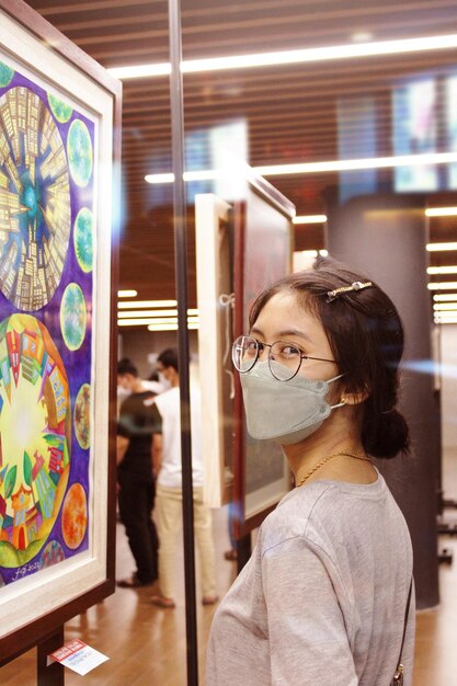 Foto una mujer con una máscara facial mira una pintura de un carnaval.