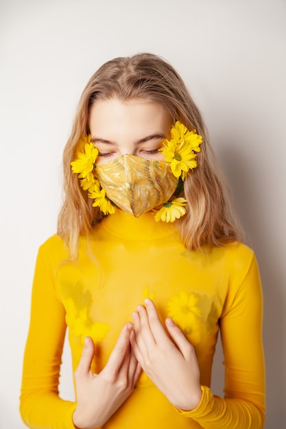 Mujer en máscara con flores amarillas en estudio