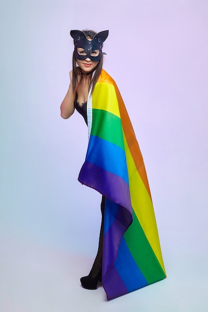 Foto una mujer con una máscara de gato sostiene una bandera del arco iris