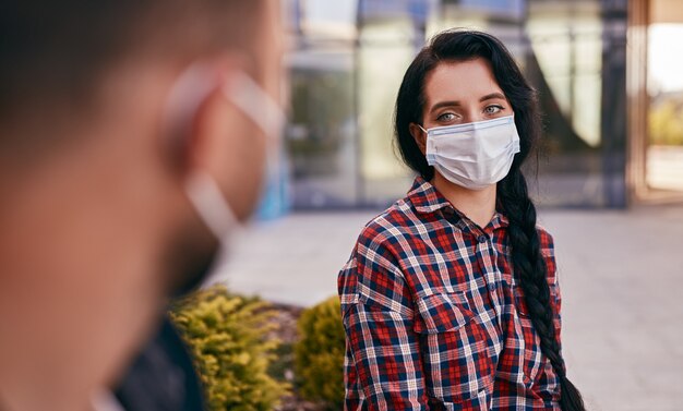 Foto mujer en máscara hablando con un amigo en la calle