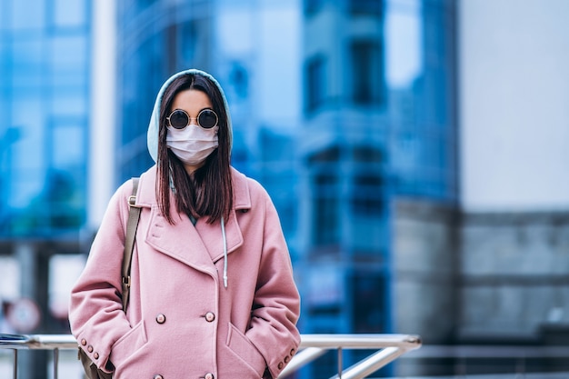 Mujer en máscara médica al aire libre en la ciudad vacía. Protección de la salud y prevención de brotes de virus, coronavirus, COVID-19, epidemia, pandemia, enfermedades infecciosas, concepto de cuarentena.