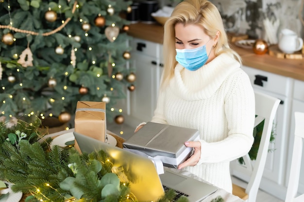 mujer con máscara médica, bokeh de árbol de navidad en el fondo.