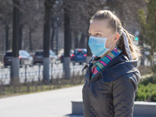 Una mujer con una máscara médica en la calle de la ciudad.