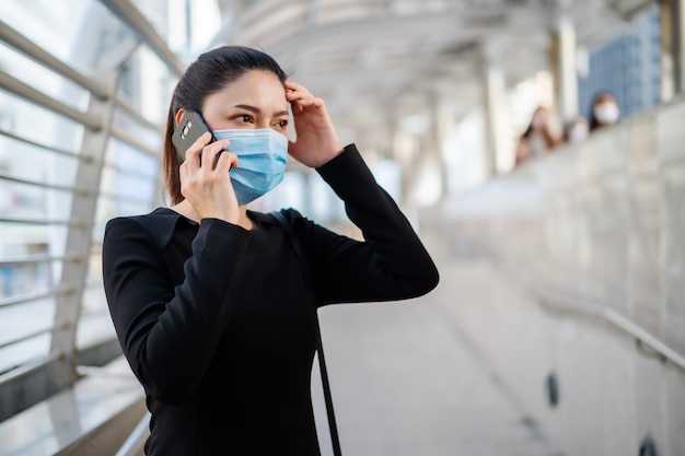 mujer con máscara médica y hablando por móvil