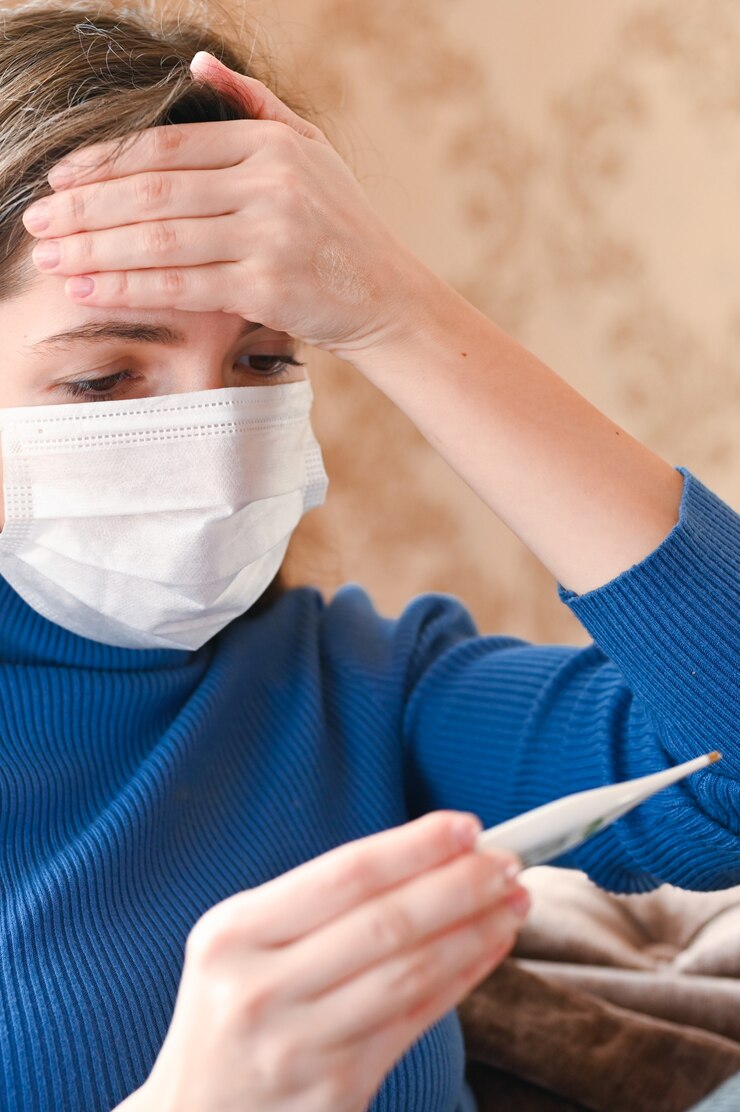 Mujer con máscara médica mide la temperatura corporal