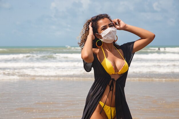 Mujer con máscara médica en la playa, nuevas reglas normales, banner web. Vida después de la pandemia, uso obligatorio de mascarilla en espacios públicos, espacio de copia