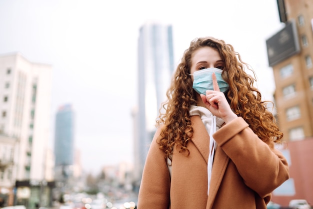 Foto mujer con máscara médica protectora estéril en su rostro muestra un gesto: shh. silencio.